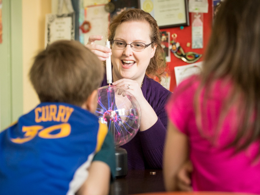 A teacher demonstrates static electricity using a plasma ball with elementary students